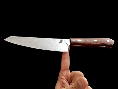 Damascus kitchen knife balanced on a finger