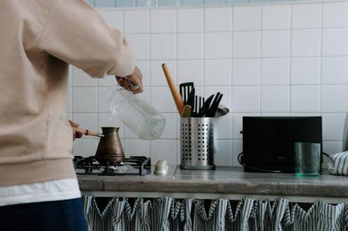 Person cooking on a stove in a fully equipped and organized kitchen Person cooking on a stove in a fully equipped and organized kitchen